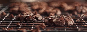 indulgent double chocolate cookies cooling on a wire rack, sprinkled with chunks of rich dark chocolate.