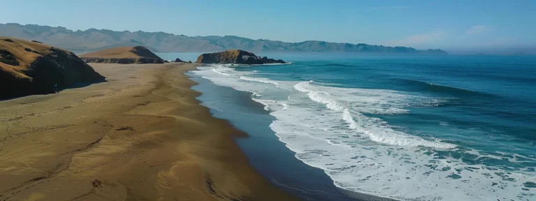 a serene beach with golden sand and crystal clear blue waves crashing gently on the shore in mocha, california.