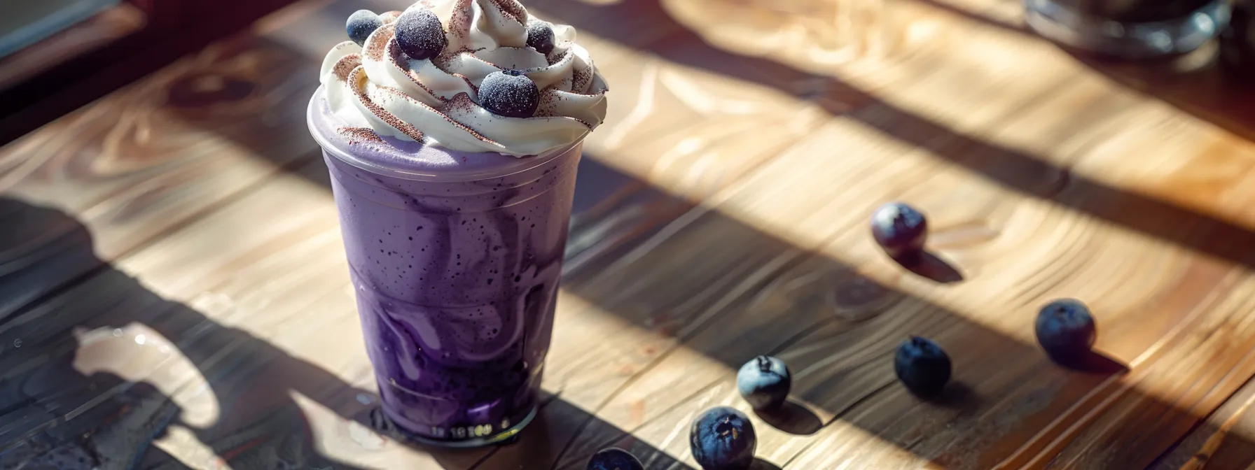 a frosty blueberry muffin frappuccino topped with whipped cream and blueberry syrup, ready to be savored on a sunny café table.